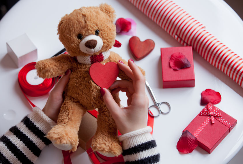 white caucasian hands holding heart shaped toy and teddy bear on the wonderful things for decoration background